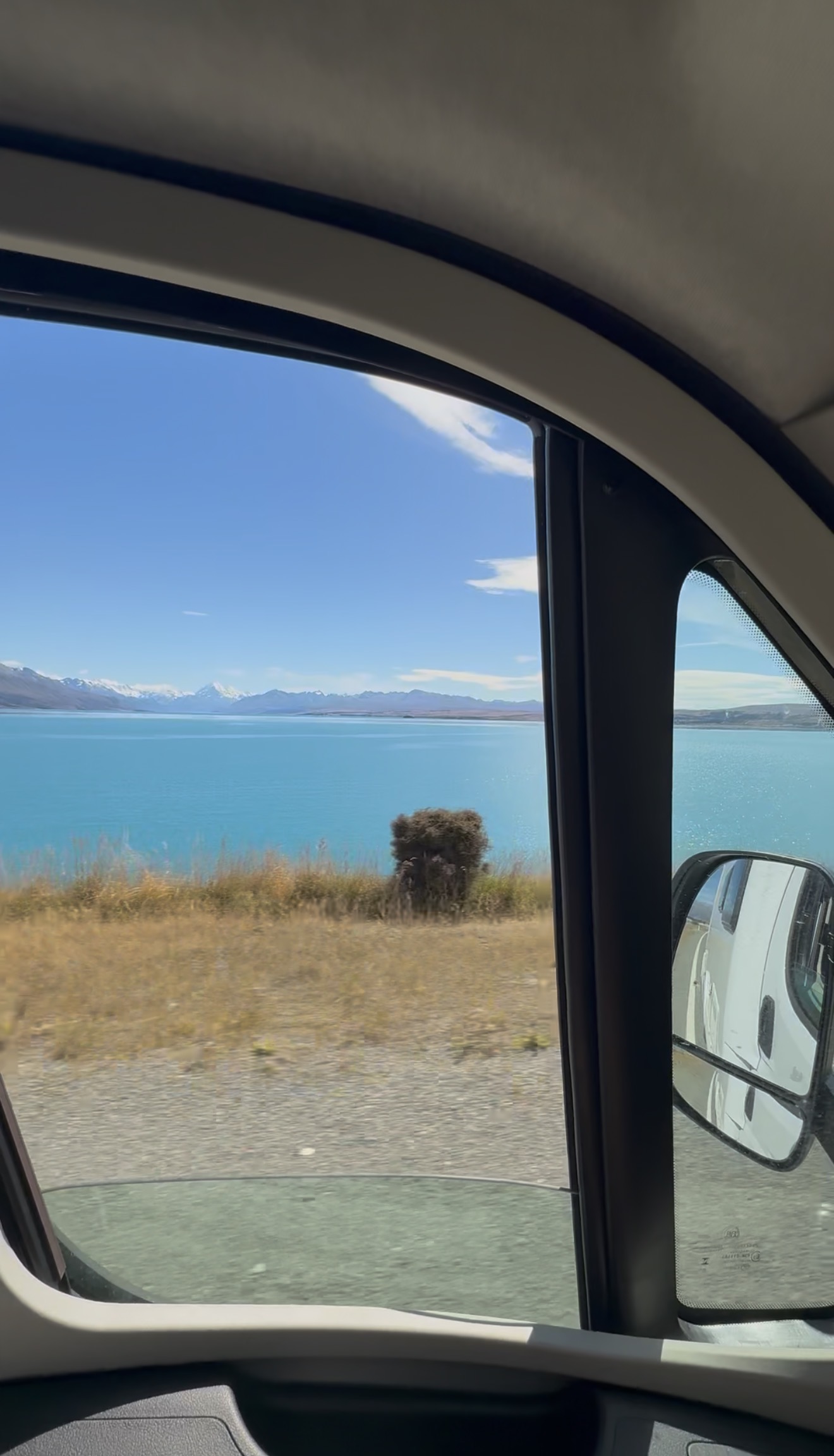 Clear blue alpine lake outside the window of a campervan in Mt. Cook New Zealand