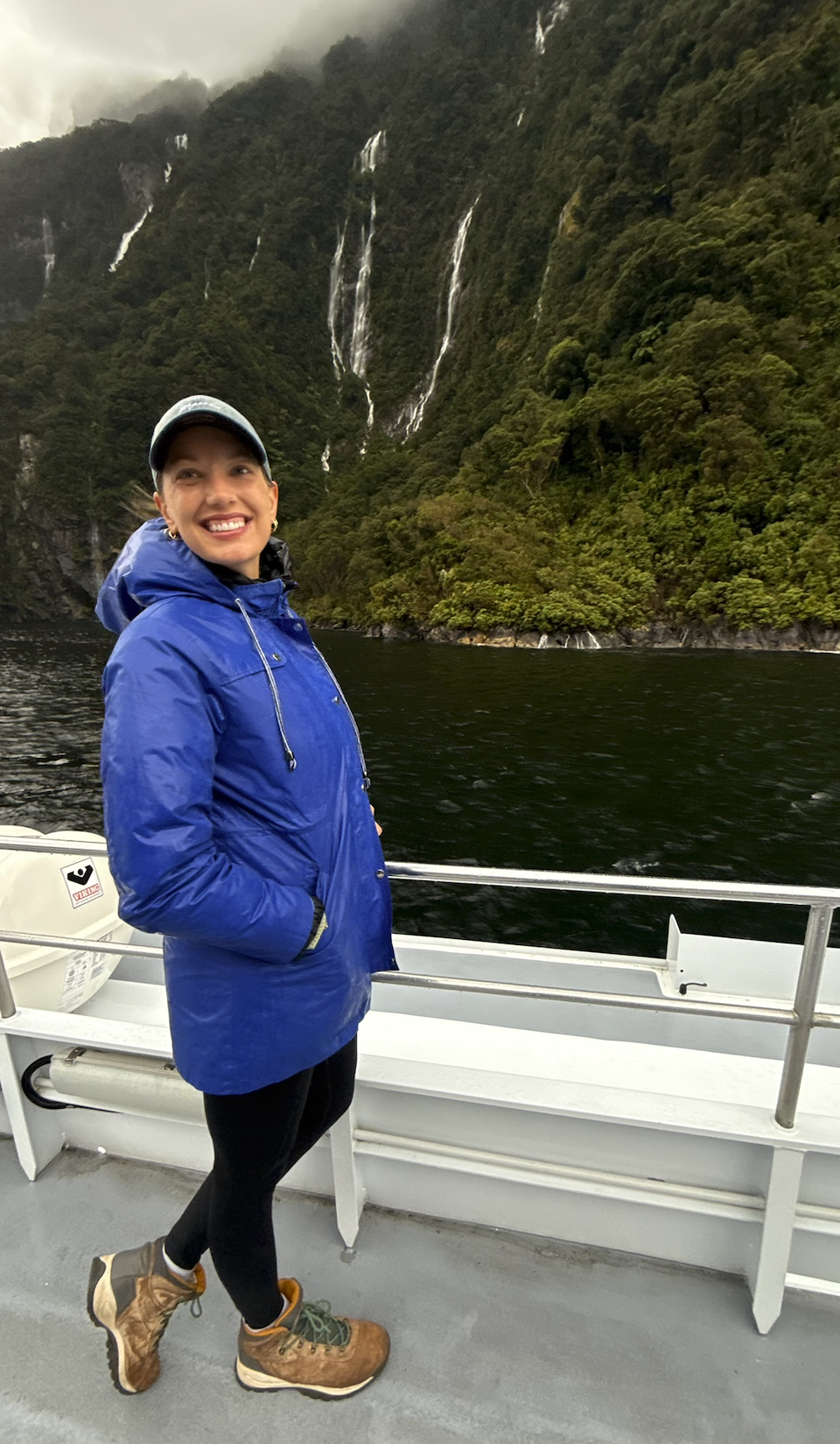 Woman in front of waterfall in Milford Sound New Zealand