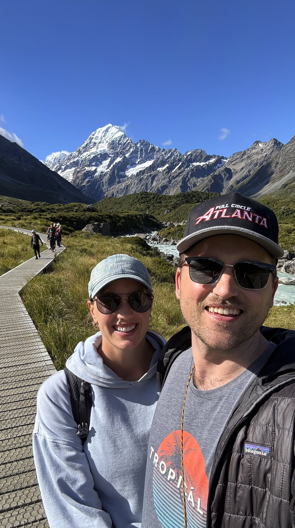 Couple hiking boardwalk of Hooker Valley Track New Zealand