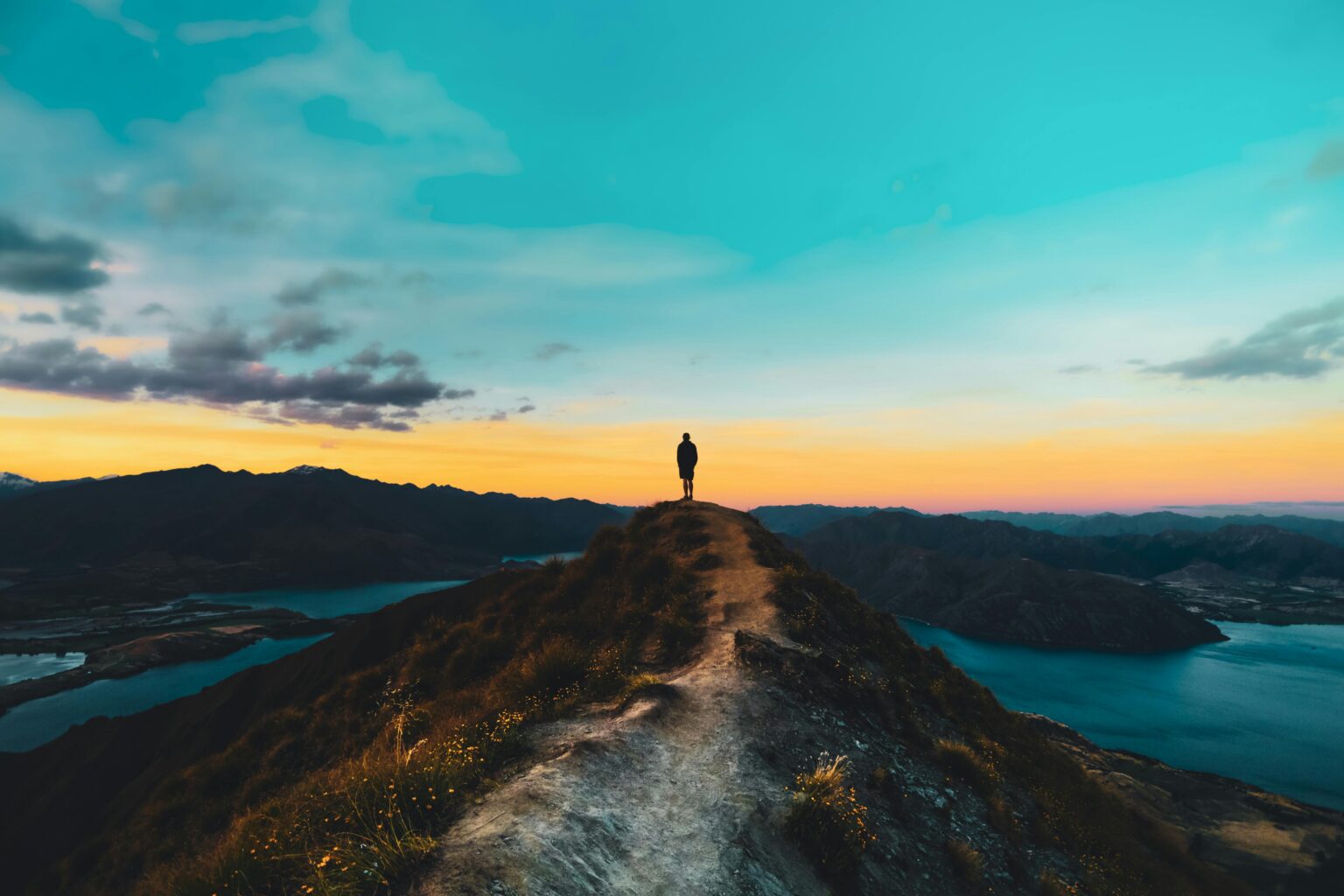 hiker on roy's peak in wanaka new zealand at sunrise