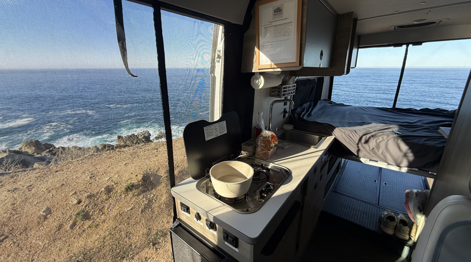 campervan with all the doors and windows open looking over the ocean on a pacific coast highway road trip